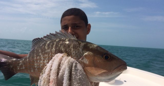 Carlos holding his first mangrove snapper he caught with Capt. Doug on a fishing charter off Marathon.